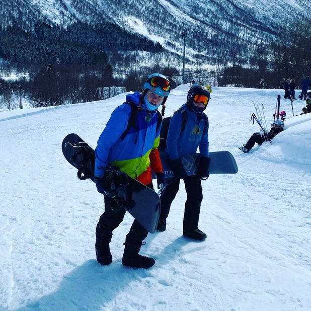 To personer med snowboard under armen opp bakke