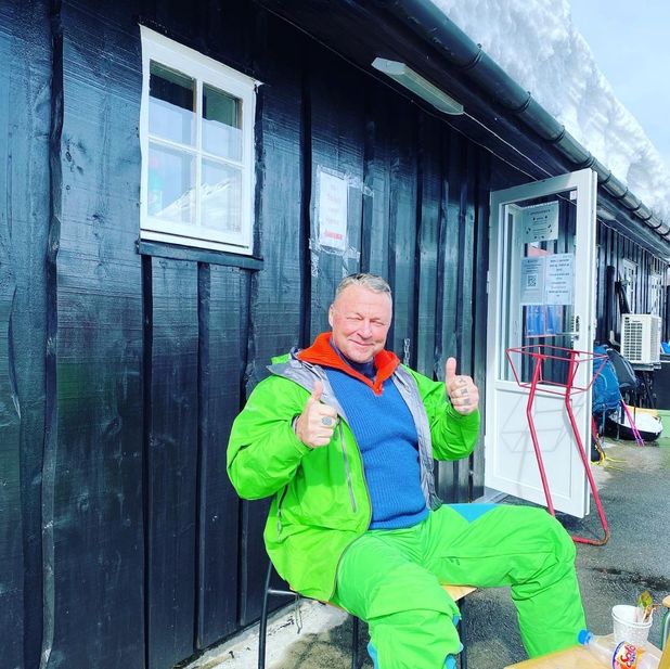 Person ved hyttevegg gir begge tomler opp